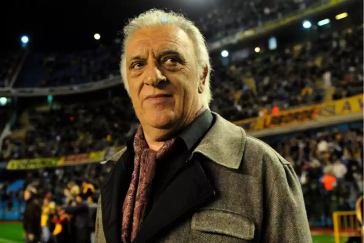 Elderly man with gray hair wearing a coat and scarf in a crowded stadium Elderly man with gray hair wearing a coat and scarf in a crowded stadium