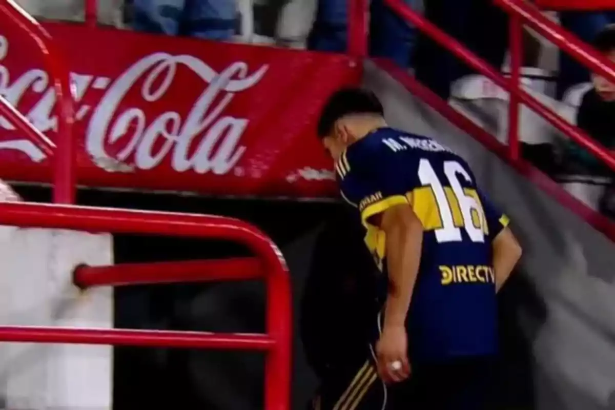 Jugador de fútbol con camiseta azul y amarilla número 16 saliendo del campo hacia el túnel en un estadio Jugador de fútbol con camiseta azul y amarilla número 16 saliendo del campo hacia el túnel en un estadio