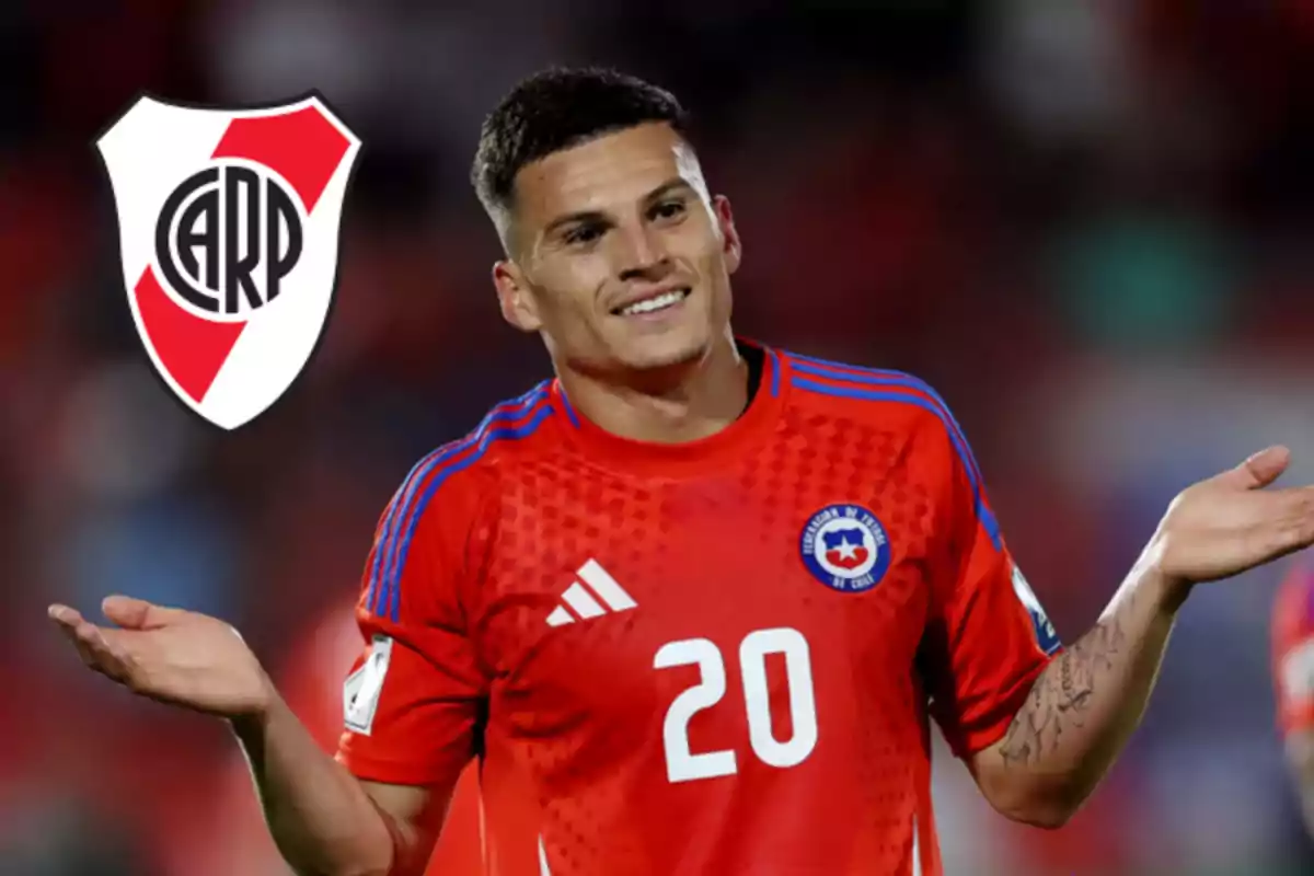 Soccer player wearing the red Chile national team jersey shrugging, with the River Plate crest in the background