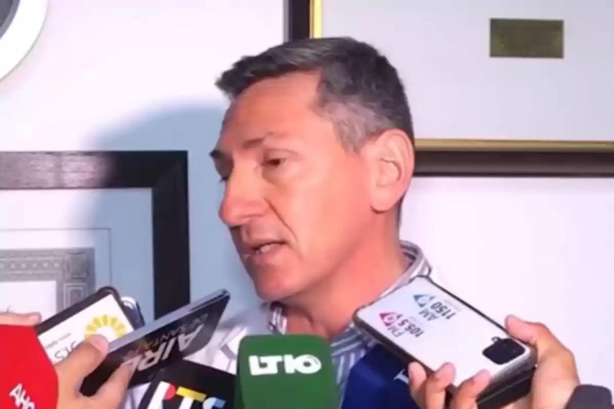 Hombre dando una entrevista rodeado de varios micrófonos y grabadoras de diferentes medios de comunicación Hombre dando una entrevista rodeado de varios micrófonos y grabadoras de diferentes medios de comunicación
