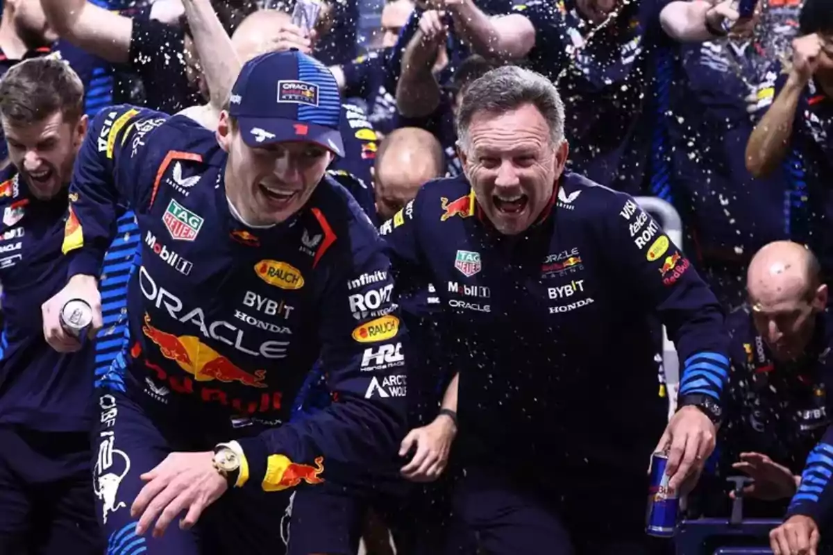 Pilotos y miembros del equipo Red Bull celebran con sonrisas y bebidas mientras salpican champán en un ambiente de fiesta Pilotos y miembros del equipo Red Bull celebran con sonrisas y bebidas mientras salpican champán en un ambiente de fiesta