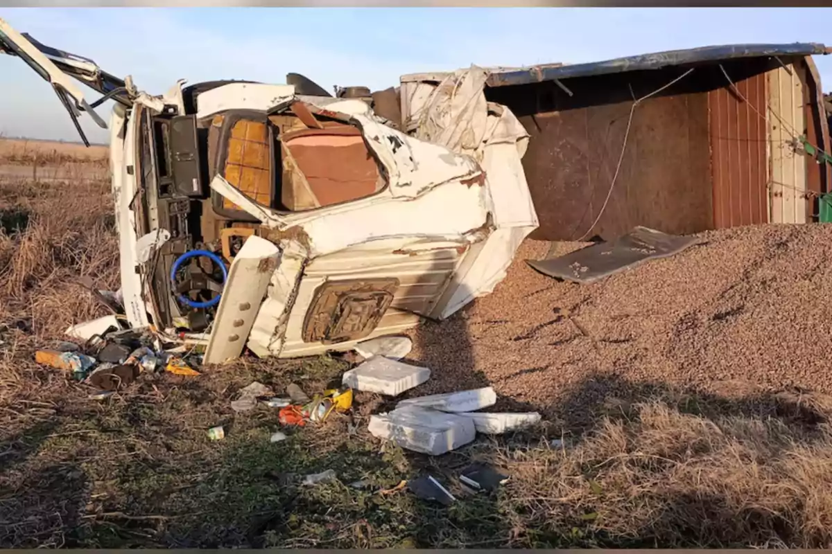 Camión volcado en la carretera con la cabina dañada y la carga derramada sobre el suelo Camión volcado en la carretera con la cabina dañada y la carga derramada sobre el suelo
