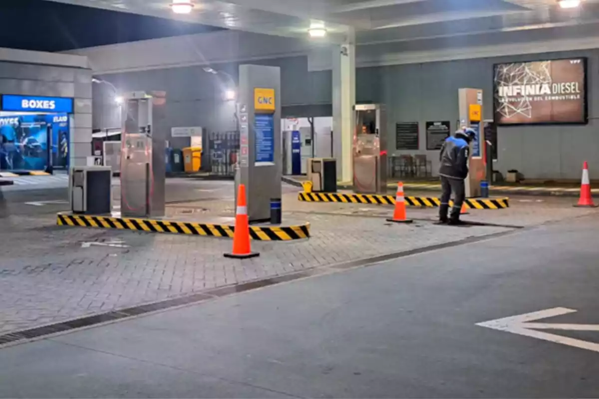 CNG service station lit up at night with orange cones and a person working next to the pumps