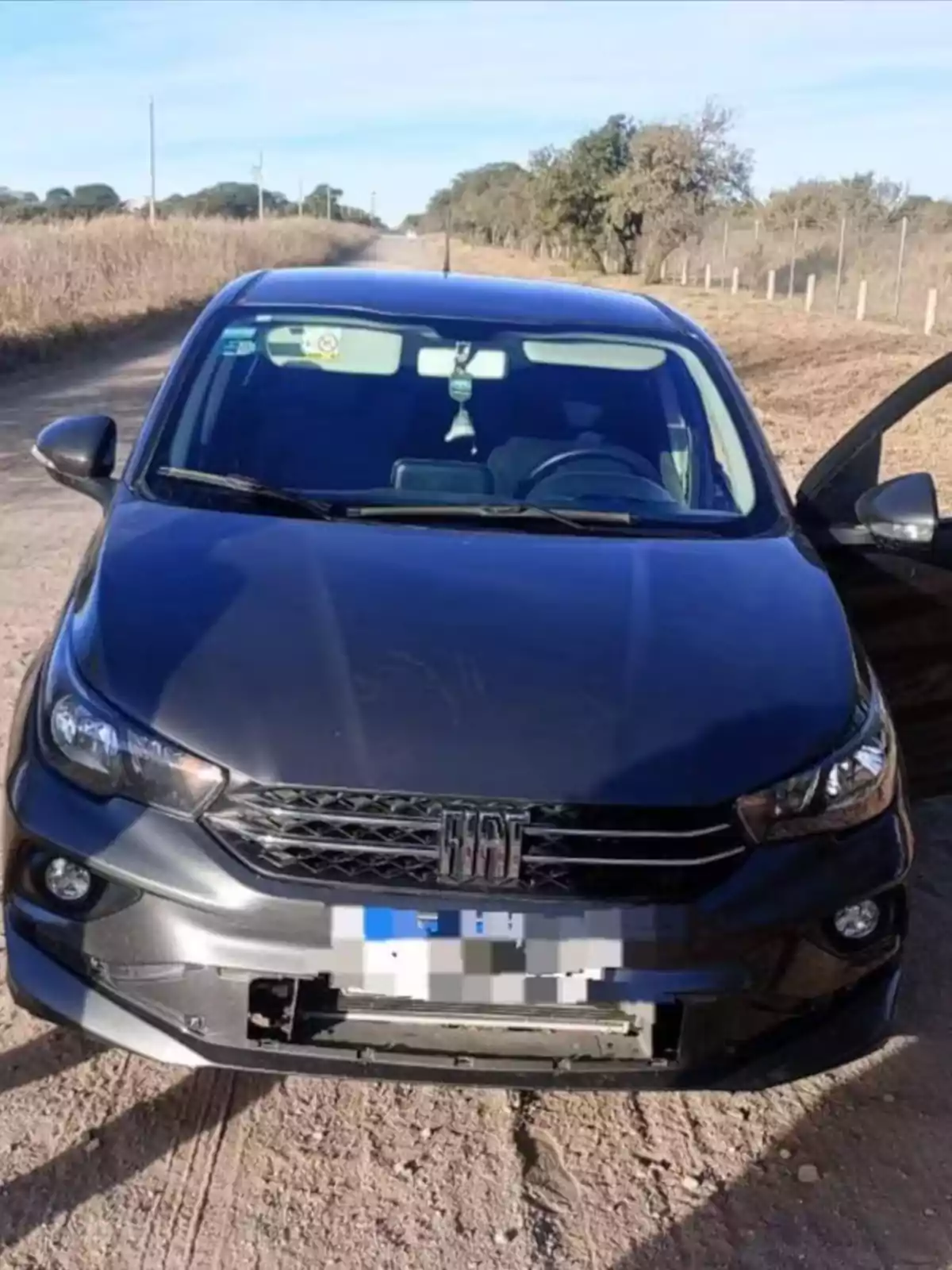 Black Fiat car parked on a dirt road with the driver’s door open and the front bumper damaged Black Fiat car parked on a dirt road with the driver’s door open and the front bumper damaged