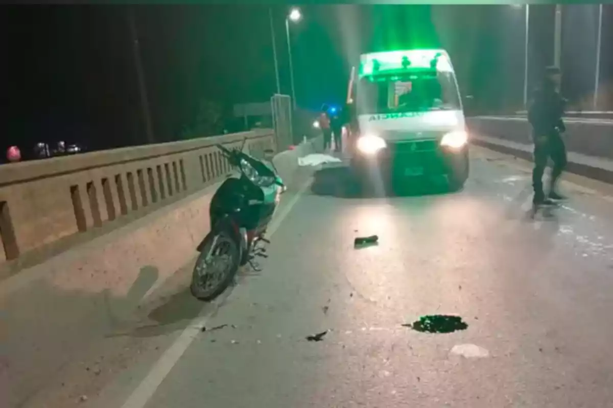 Crashed motorcycle on a bridge at night with an ambulance and emergency personnel at the scene Crashed motorcycle on a bridge at night with an ambulance and emergency personnel at the scene