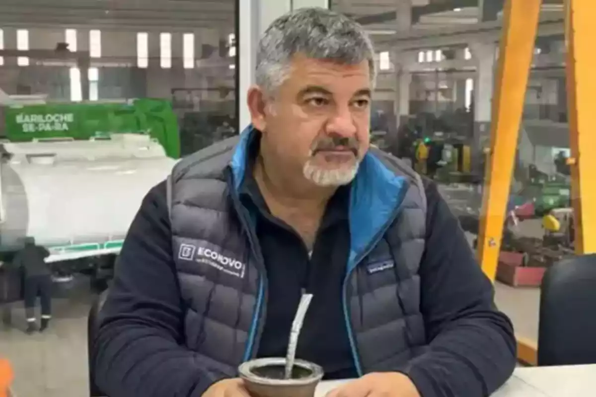 Gray-haired, bearded man sitting at a table holding a mate in a factory or industrial workshop Gray-haired, bearded man sitting at a table holding a mate in a factory or industrial workshop