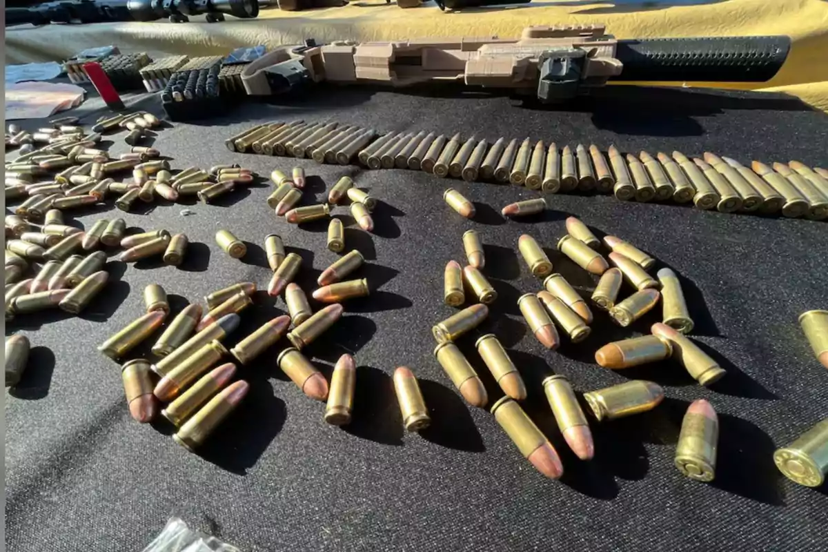 Cartridges of different calibers scattered on a black table with a long gun in the background Cartridges of different calibers scattered on a black table with a long gun in the background