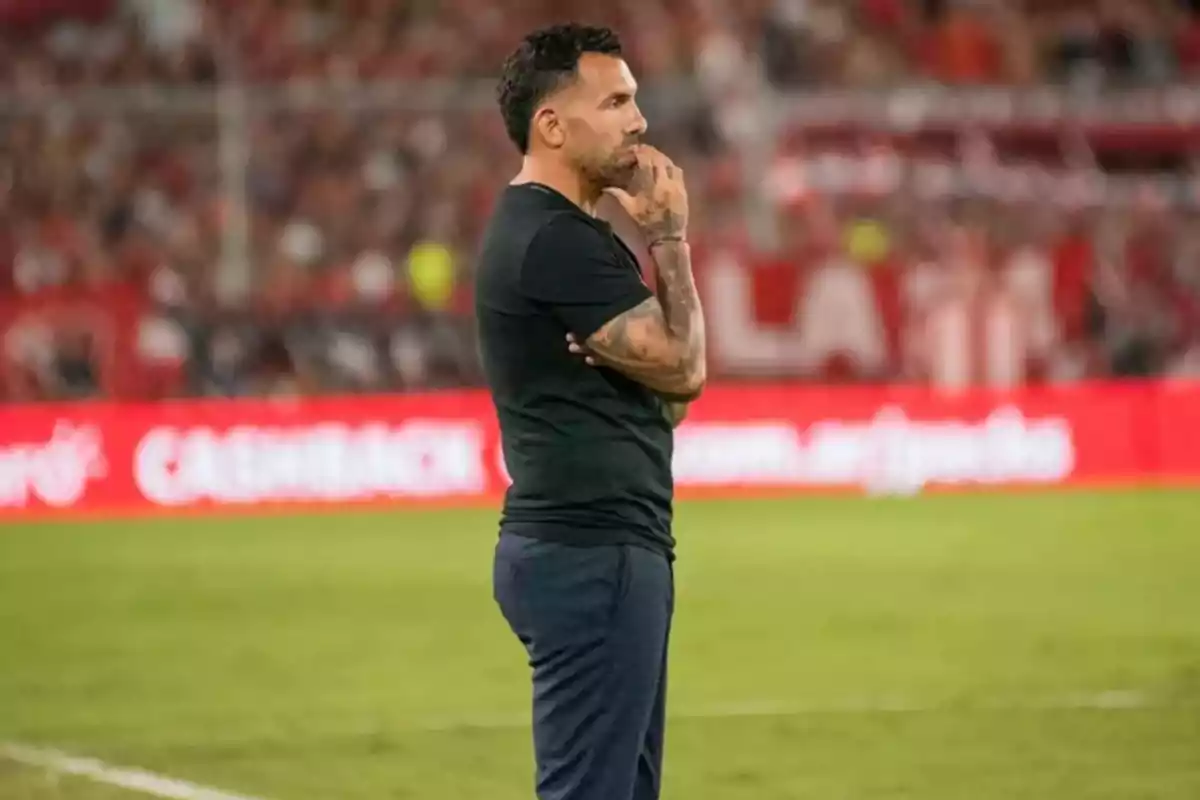 Man standing on the soccer field with a thoughtful expression and a stadium full of spectators in the background Man standing on the soccer field with a thoughtful expression and a stadium full of spectators in the background