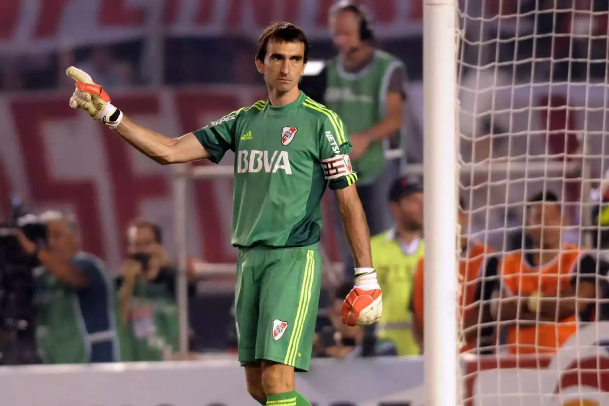 Portero de River Plate con uniforme verde y brazalete de capitán señalando con la mano durante un partido de fútbol
