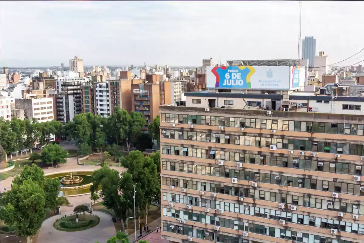 Vista aérea de un edificio gubernamental con un cartel que dice Palacio 6 de Julio rodeado de árboles y una plaza con una fuente en el centro de la ciudad Vista aérea de un edificio gubernamental con un cartel que dice Palacio 6 de Julio rodeado de árboles y una plaza con una fuente en el centro de la ciudad