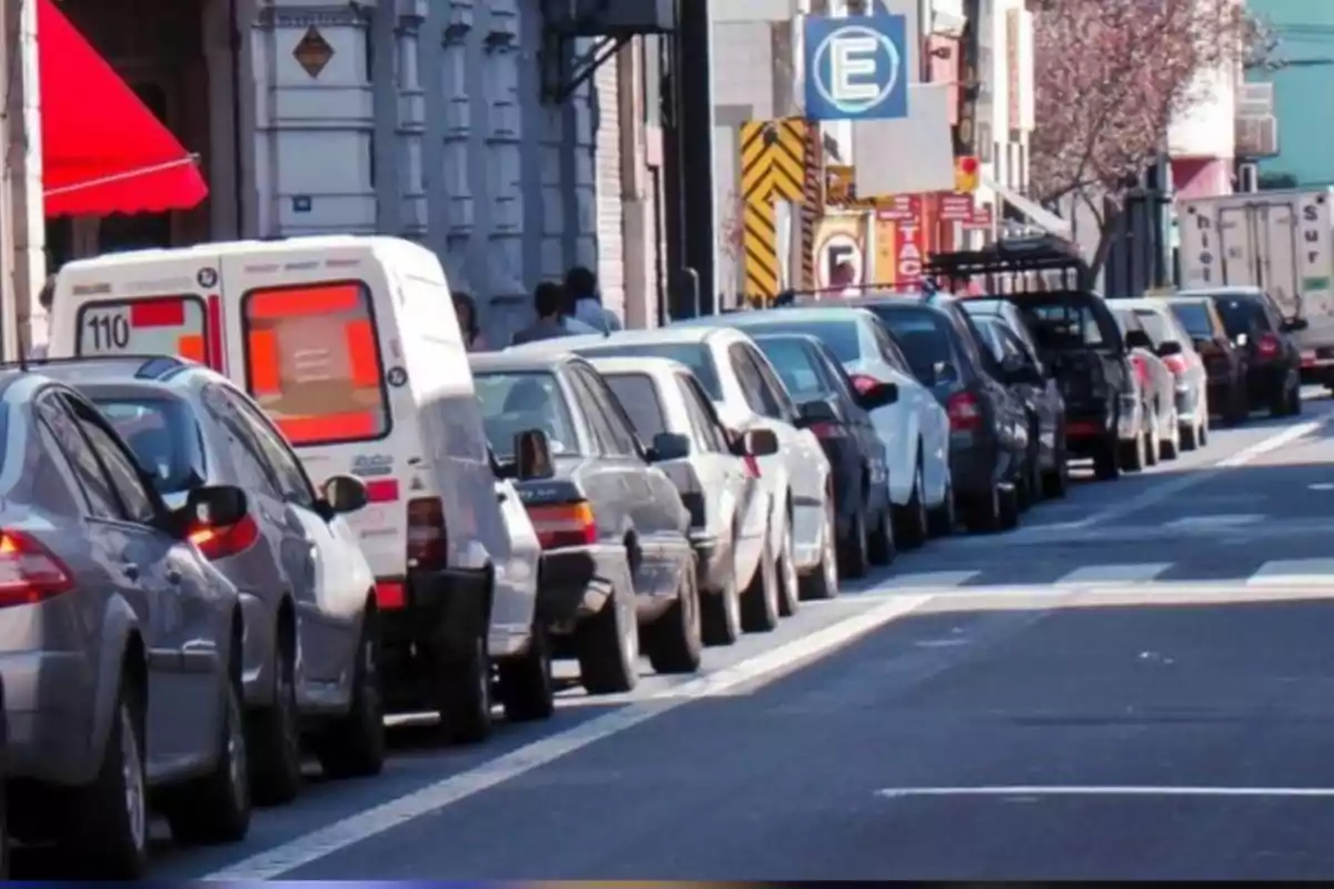 Varios autos estacionados en fila a lo largo de una calle urbana durante el día