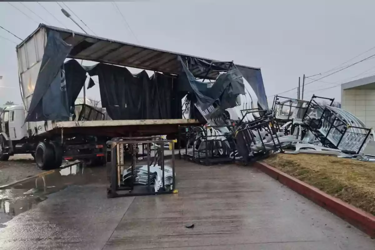 Trailer with a torn tarp and a load of metal structures fallen onto the sidewalk on a rainy day Trailer with a torn tarp and a load of metal structures fallen onto the sidewalk on a rainy day