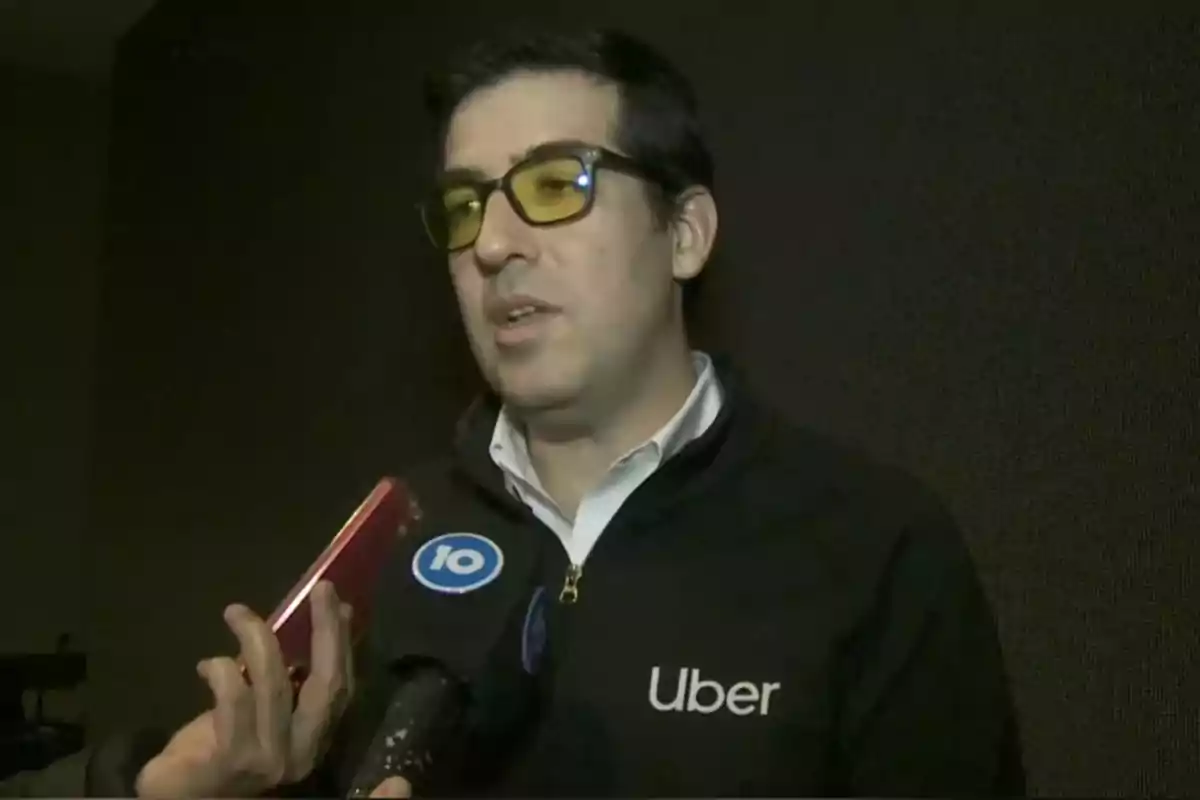 Hombre con gafas y chaqueta de Uber siendo entrevistado por la prensa Hombre con gafas y chaqueta de Uber siendo entrevistado por la prensa