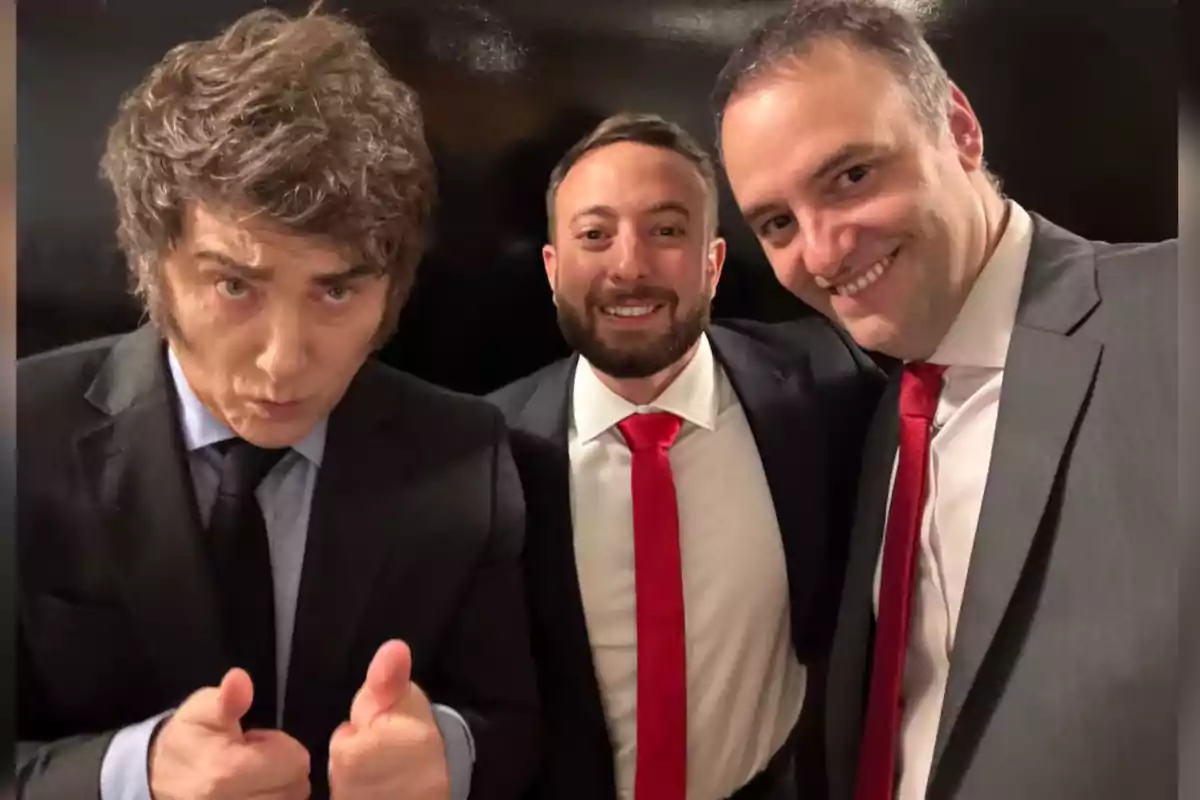 Three men dressed in suits pose together for a photo; two of them are smiling and one is giving a thumbs-up with both hands. Three men dressed in suits pose together for a photo; two of them are smiling and one is giving a thumbs-up with both hands.