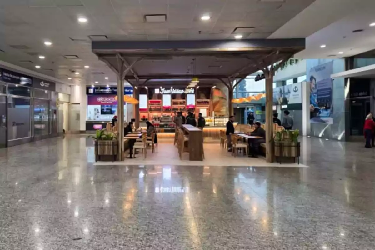 Cafetería Juan Valdez en el centro de un pasillo amplio de centro comercial con varias personas sentadas en las mesas Cafetería Juan Valdez en el centro de un pasillo amplio de centro comercial con varias personas sentadas en las mesas