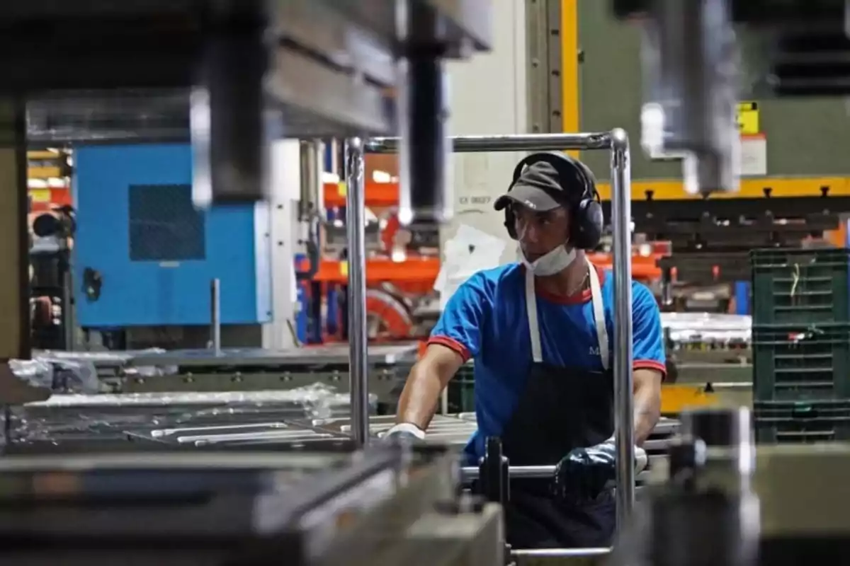 Trabajador operando maquinaria industrial en una fábrica usando equipo de protección personal Trabajador operando maquinaria industrial en una fábrica usando equipo de protección personal