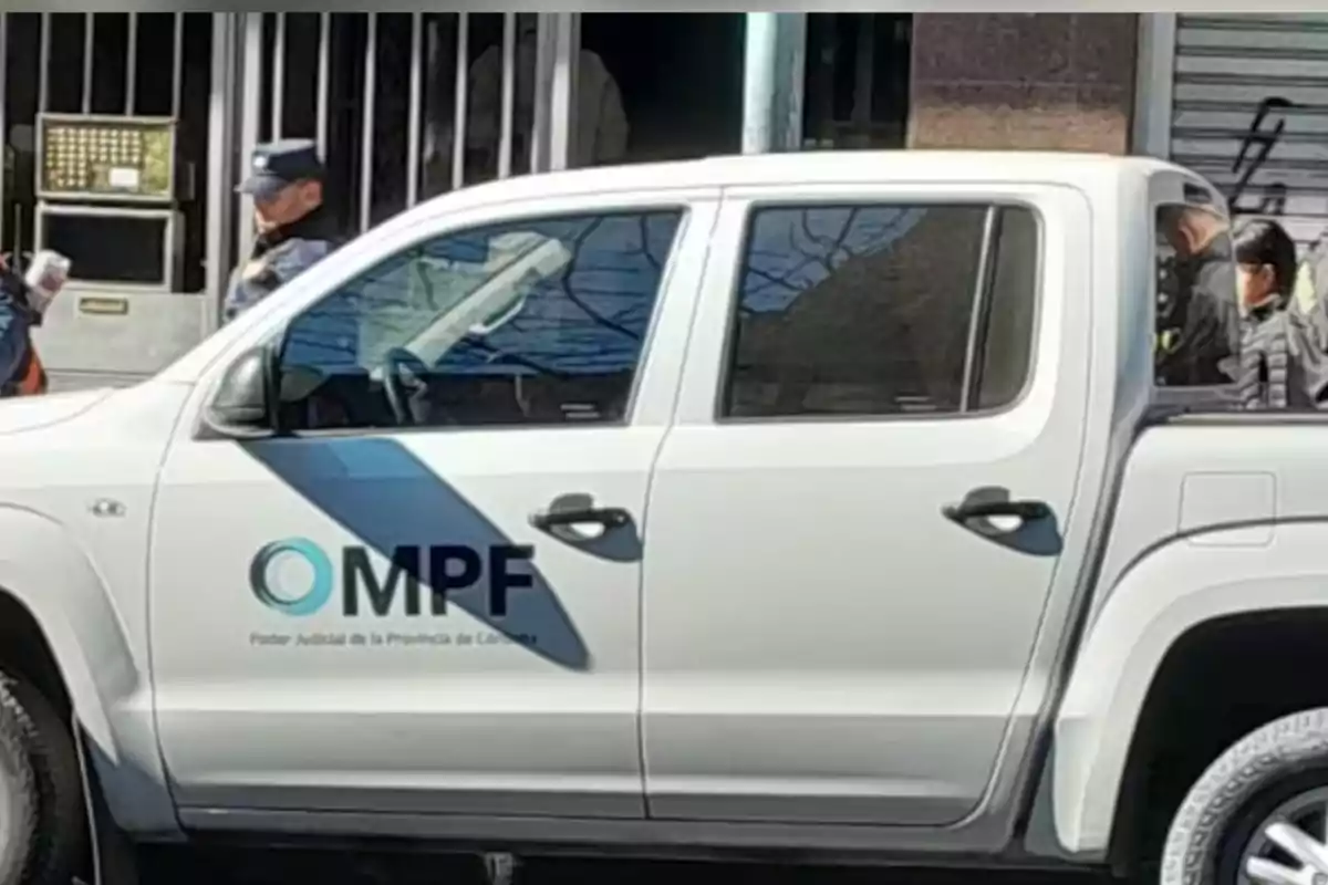 White pickup truck from the Public Prosecutor's Office parked in front of a building with police officers around. White pickup truck from the Public Prosecutor's Office parked in front of a building with police officers around.