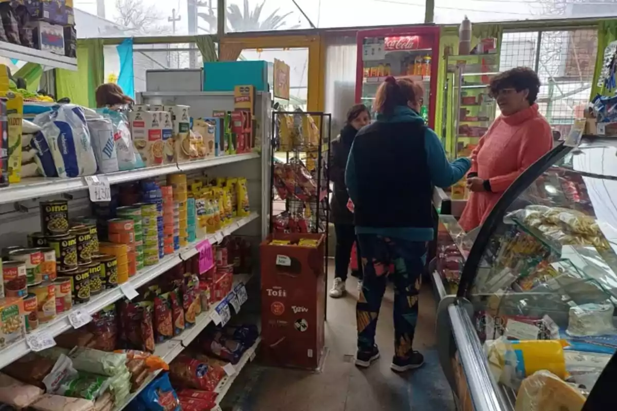 People talking inside a grocery store with shelves full of products and a beverage refrigerator in the background. People talking inside a grocery store with shelves full of products and a beverage refrigerator in the background.