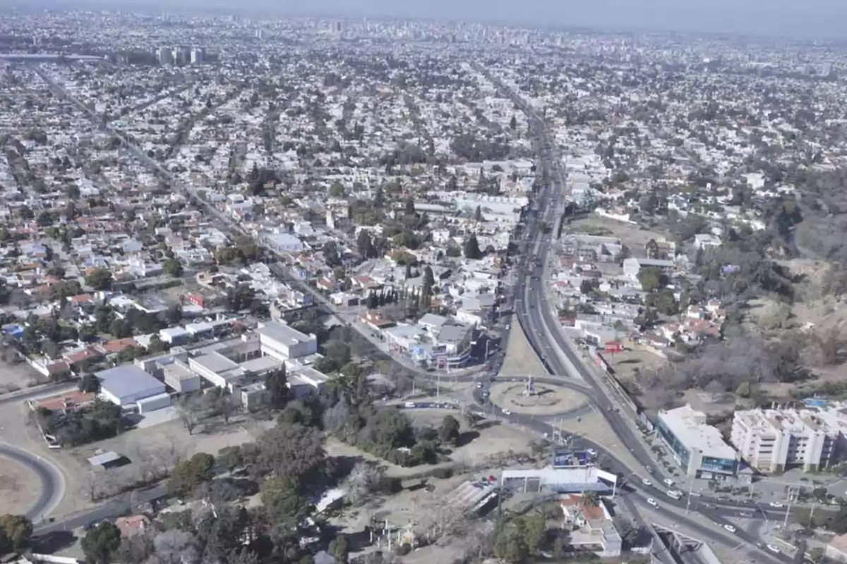 Aerial view of a city with a main avenue and a roundabout surrounded by buildings and houses Aerial view of a city with a main avenue and a roundabout surrounded by buildings and houses