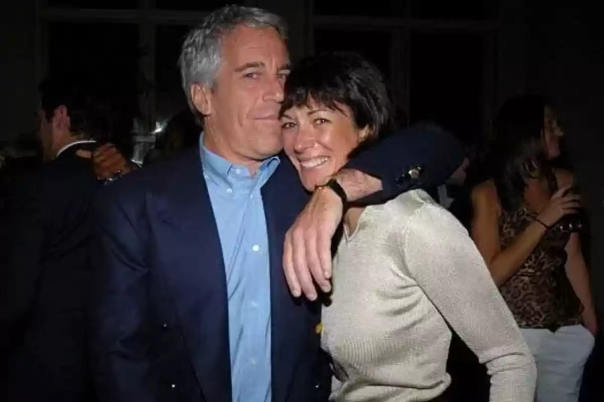 Dos personas abrazadas y sonriendo en una fiesta con otras personas al fondo Dos personas abrazadas y sonriendo en una fiesta con otras personas al fondo