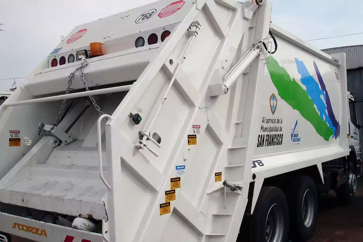 Camión recolector de basura blanco con gráficos de colores y logotipos municipales estacionado en la vía pública Camión recolector de basura blanco con gráficos de colores y logotipos municipales estacionado en la vía pública