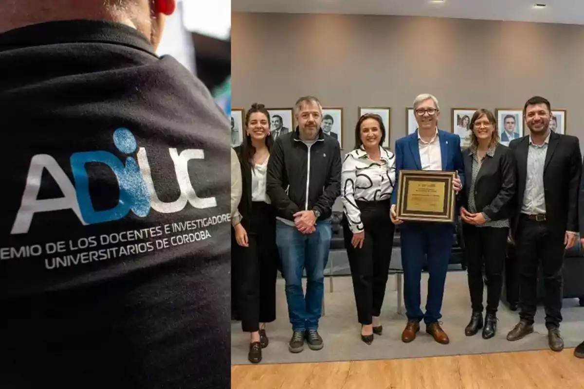 Grupo de personas posando con una placa de reconocimiento y una camiseta con el logo de ADIUC en primer plano