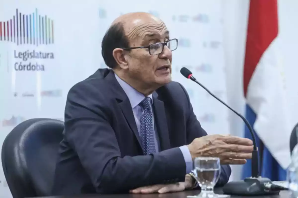 Hombre de traje y gafas hablando en un micrófono durante una conferencia en la Legislatura de Córdoba Hombre de traje y gafas hablando en un micrófono durante una conferencia en la Legislatura de Córdoba