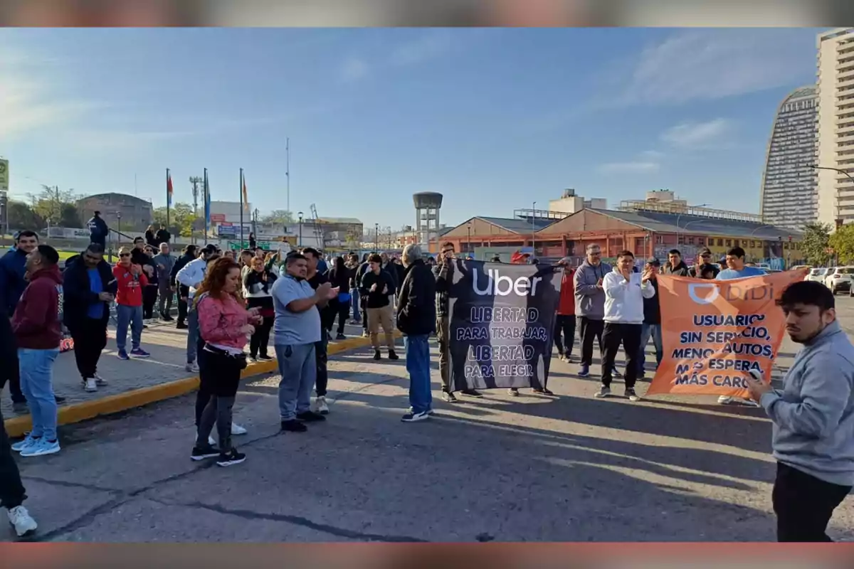 A group of people is protesting in the street holding Uber and Didi signs in a city under a clear sky. A group of people is protesting in the street holding Uber and Didi signs in a city under a clear sky.