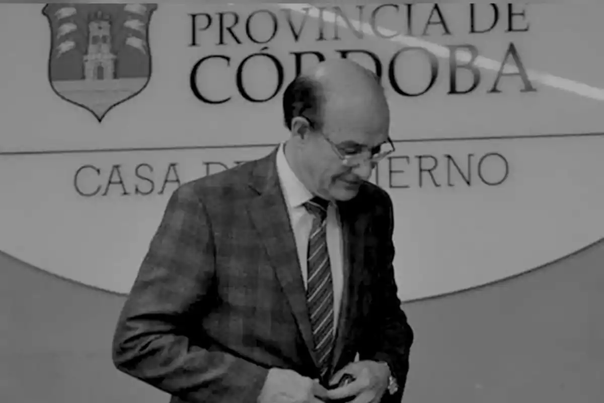 Hombre de traje y corbata caminando frente a un cartel que dice Provincia de Córdoba Casa de Gobierno
