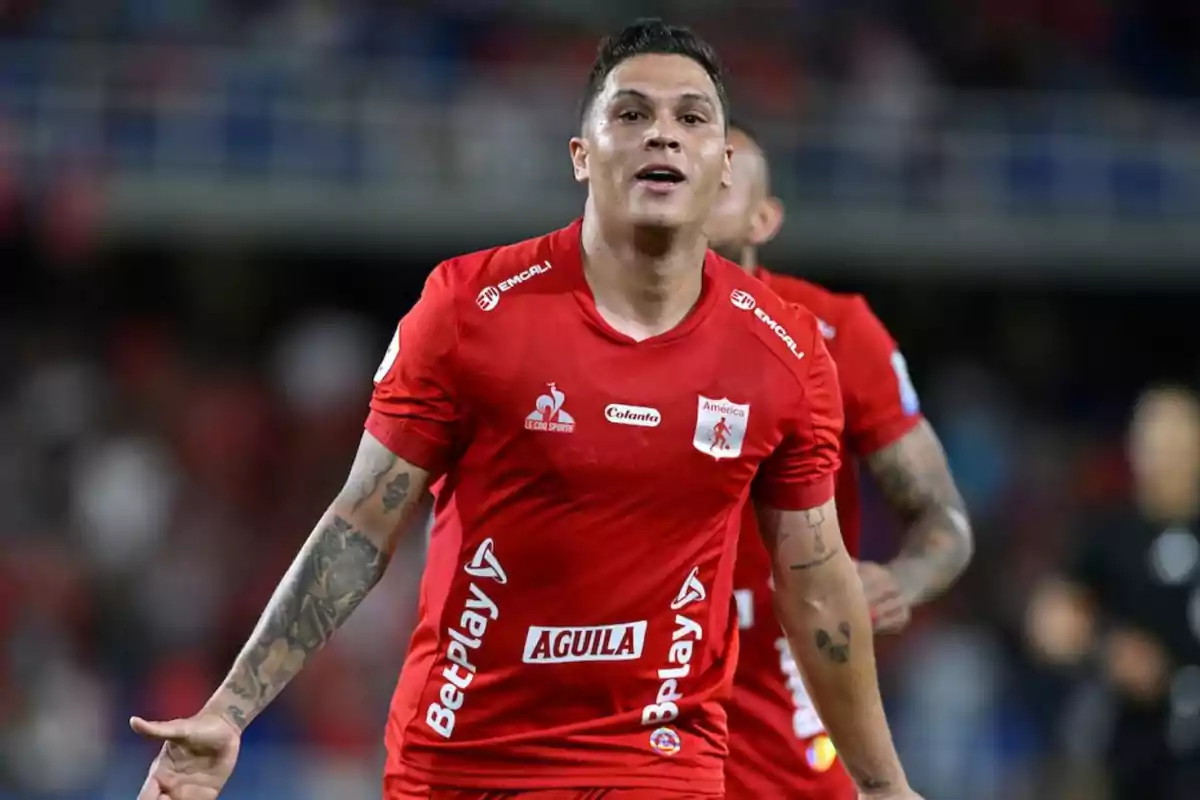 Soccer player in a red América de Cali uniform celebrating in a stadium during a match Soccer player in a red América de Cali uniform celebrating in a stadium during a match