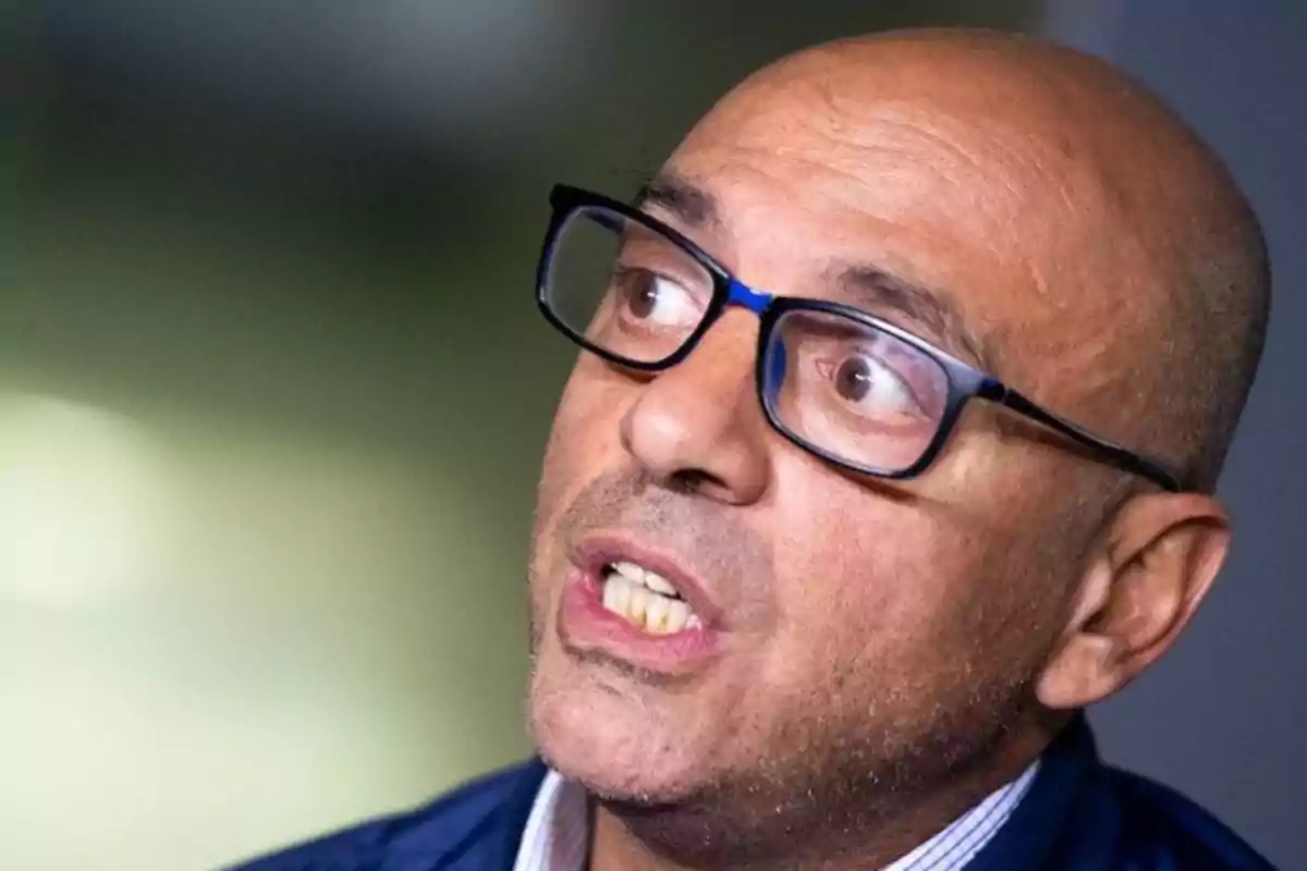 Hombre calvo con gafas oscuras y expresión facial de sorpresa o preocupación