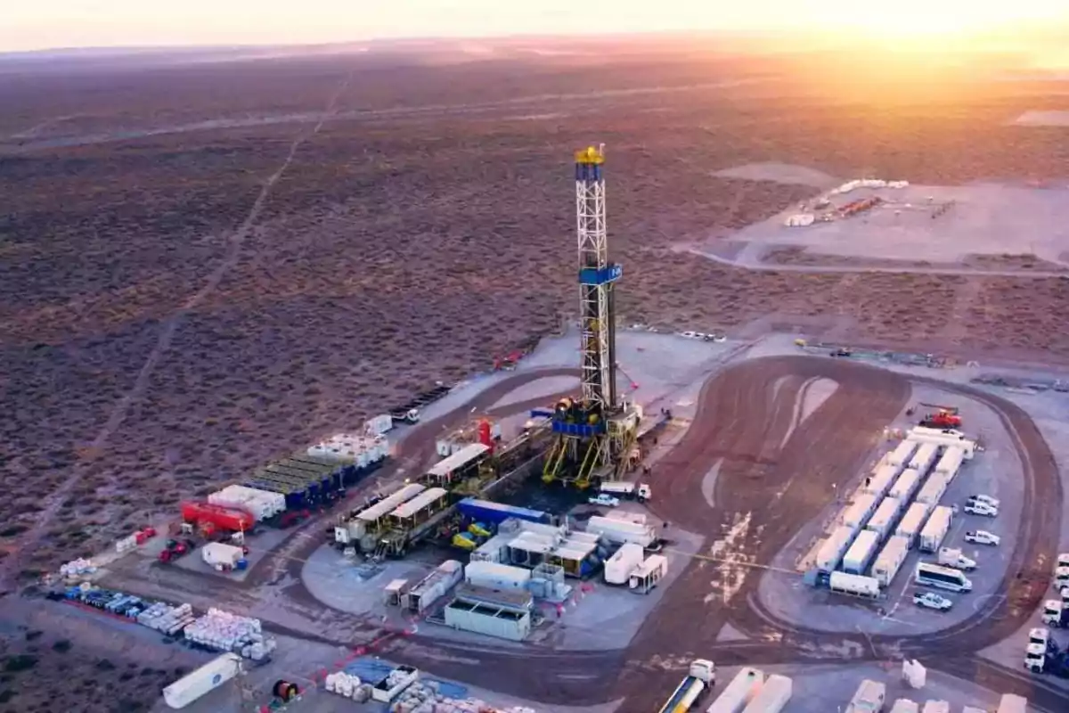 Plataforma petrolera en medio del desierto al atardecer con varios camiones y equipos alrededor Plataforma petrolera en medio del desierto al atardecer con varios camiones y equipos alrededor