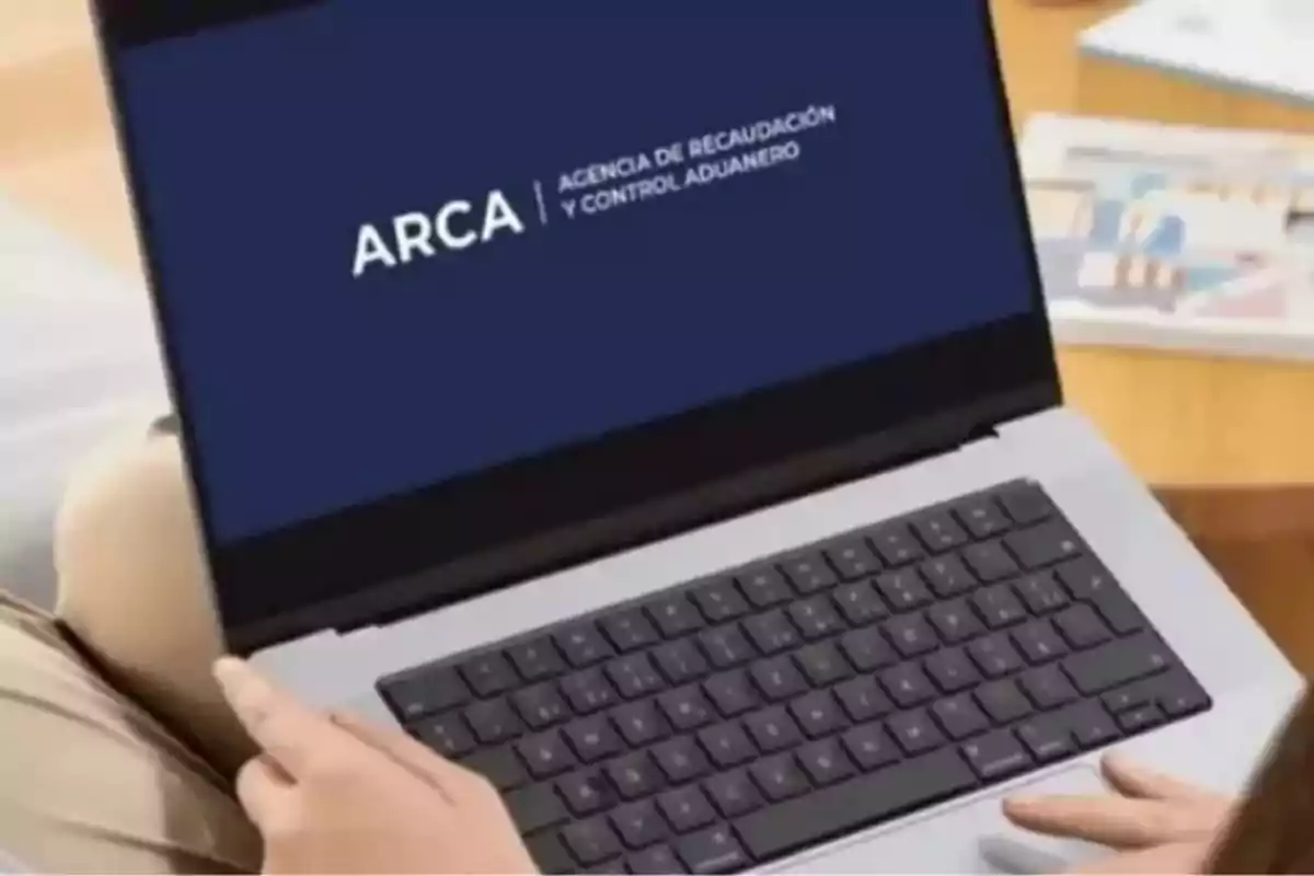 Persona usando una laptop que muestra en pantalla el logo de la Agencia de Recaudación y Control Aduanero ARCA