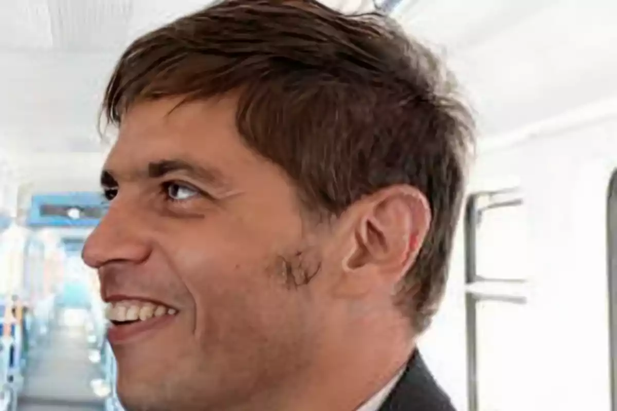 Hombre sonriente de perfil dentro de un vagón de tren iluminado