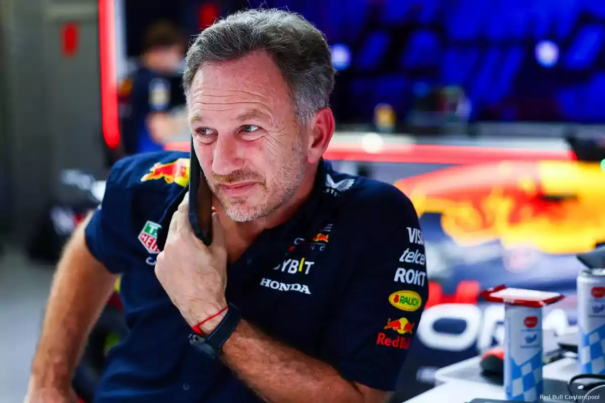 Man in Red Bull Racing uniform talking on the phone in a Formula 1 team environment