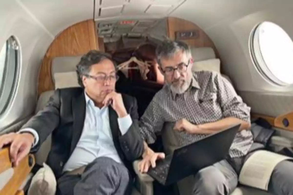 Two men sitting on a private plane watch the screen of a laptop. Two men sitting on a private plane watch the screen of a laptop.
