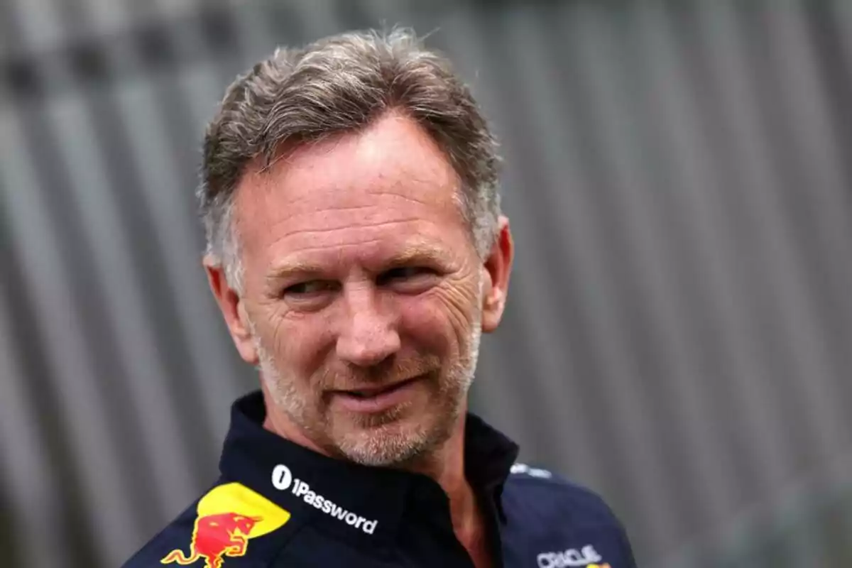 Short-haired, bearded man in a blue Red Bull jersey looking to the side with a smiling expression