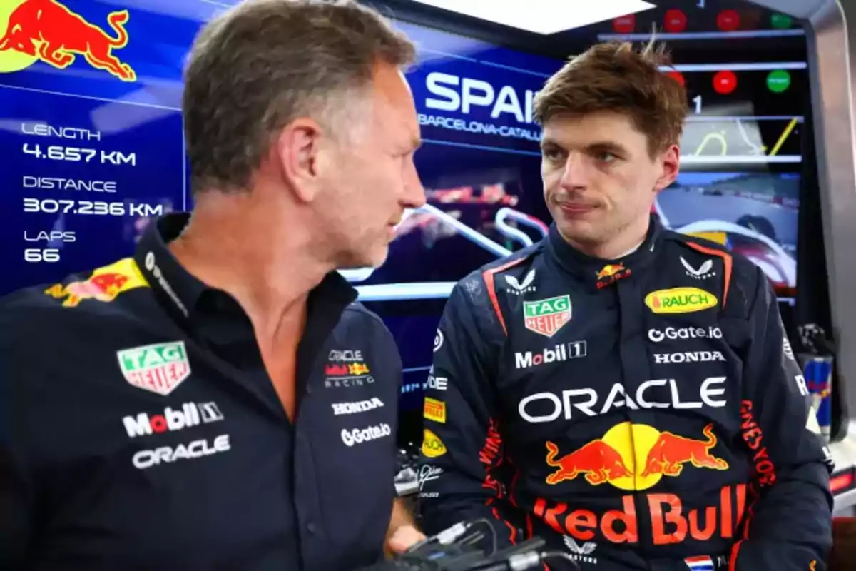 Two members of the Red Bull Formula 1 team talk in the garage during the Spanish Grand Prix, with circuit information visible in the background. Two members of the Red Bull Formula 1 team talk in the garage during the Spanish Grand Prix, with circuit information visible in the background.