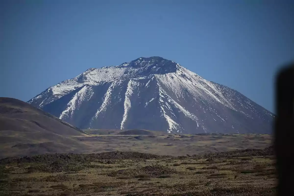 Montaña nevada bajo un cielo despejado con un paisaje árido en primer plano