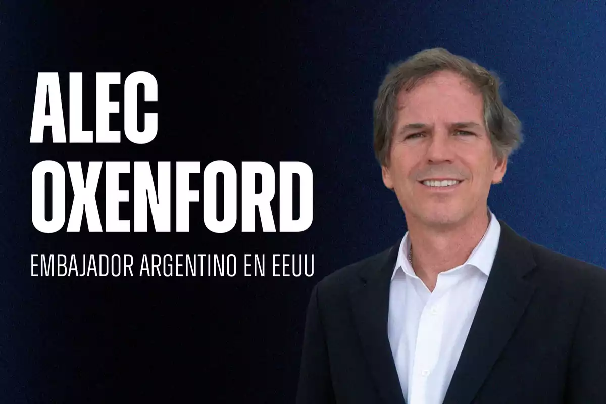 Hombre de cabello castaño claro y saco oscuro sonríe frente a un fondo azul con el texto Alec Oxenford Embajador argentino en EEUU