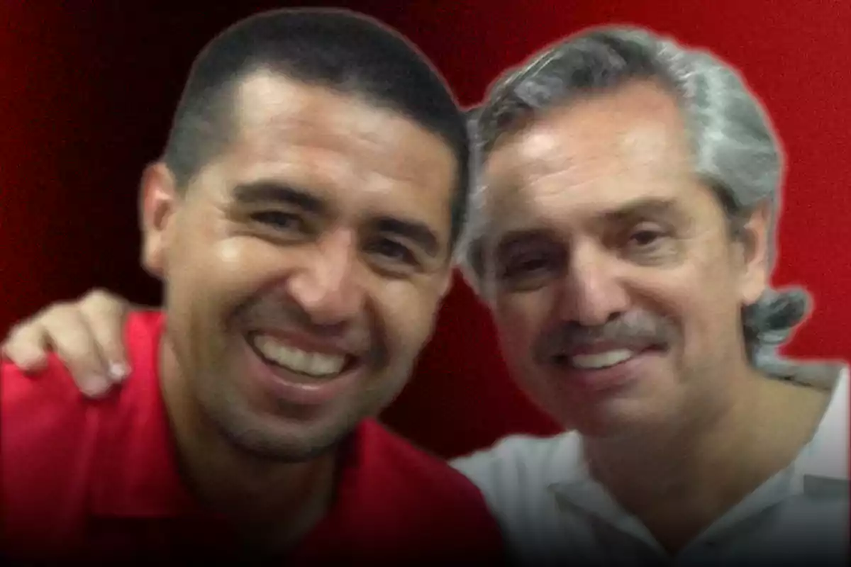 Dos personas sonríen y posan juntas frente a un fondo rojo