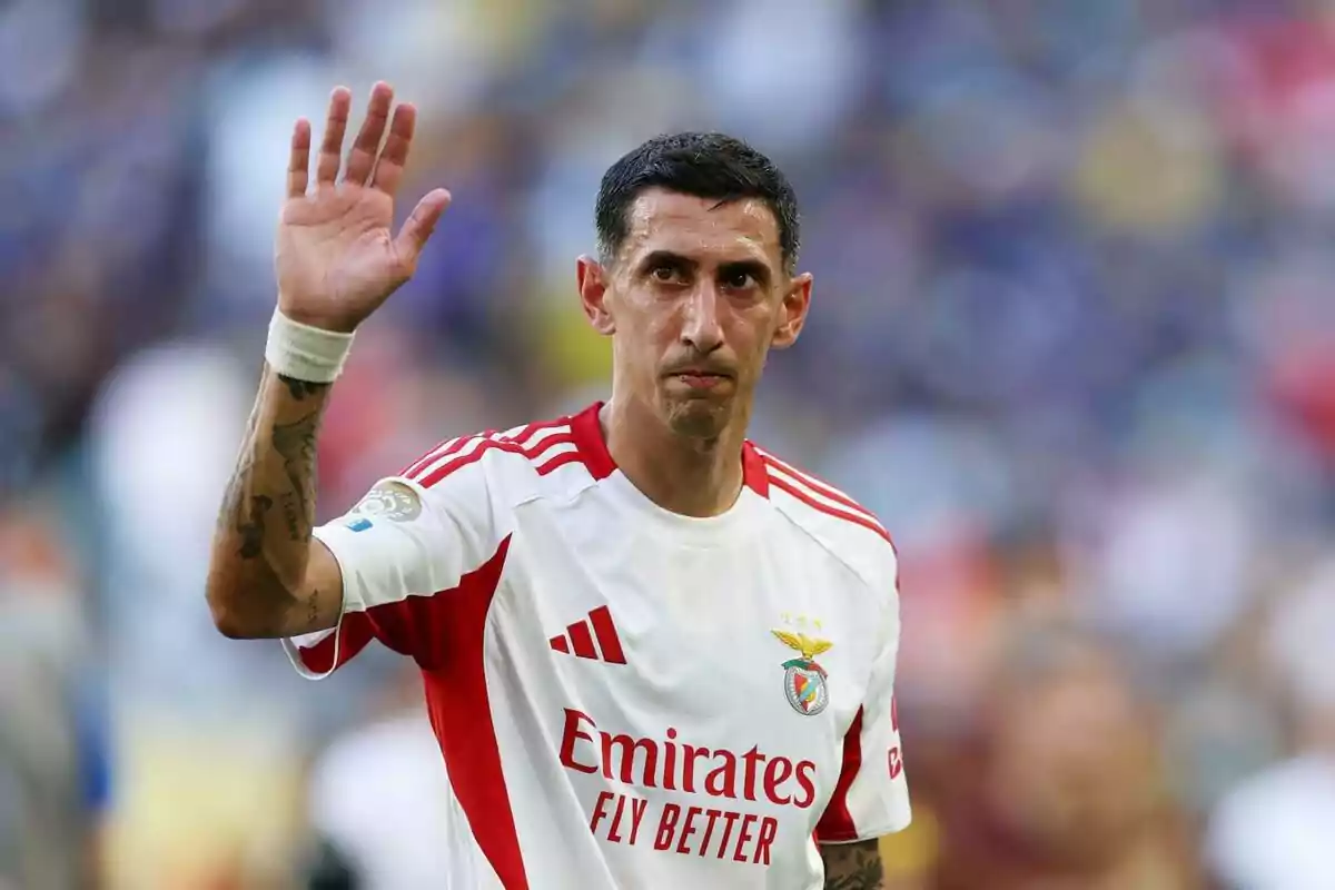 Futbolista con uniforme blanco y rojo del Benfica levantando la mano en señal de saludo durante un partido Futbolista con uniforme blanco y rojo del Benfica levantando la mano en señal de saludo durante un partido