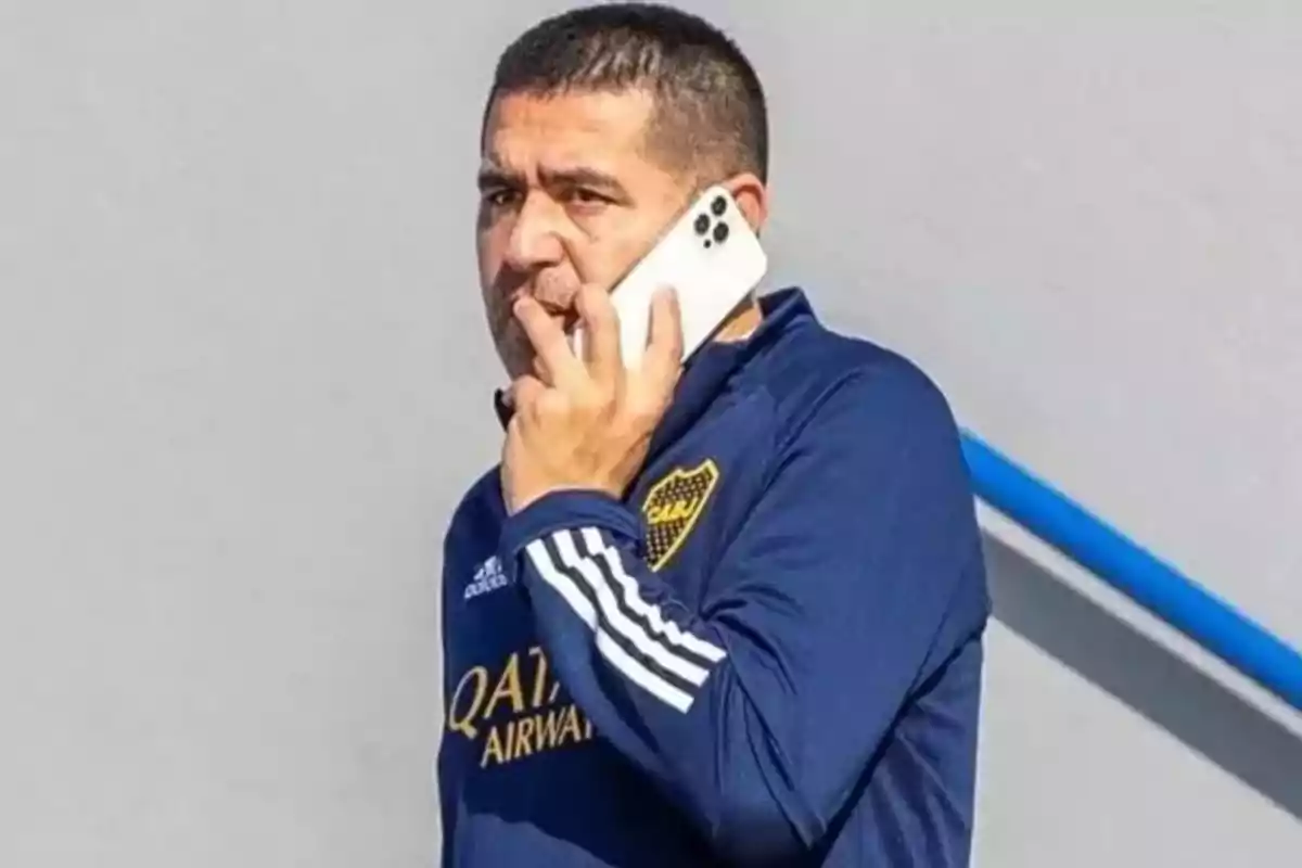 Man wearing blue Boca Juniors sportswear talking on a white cell phone
