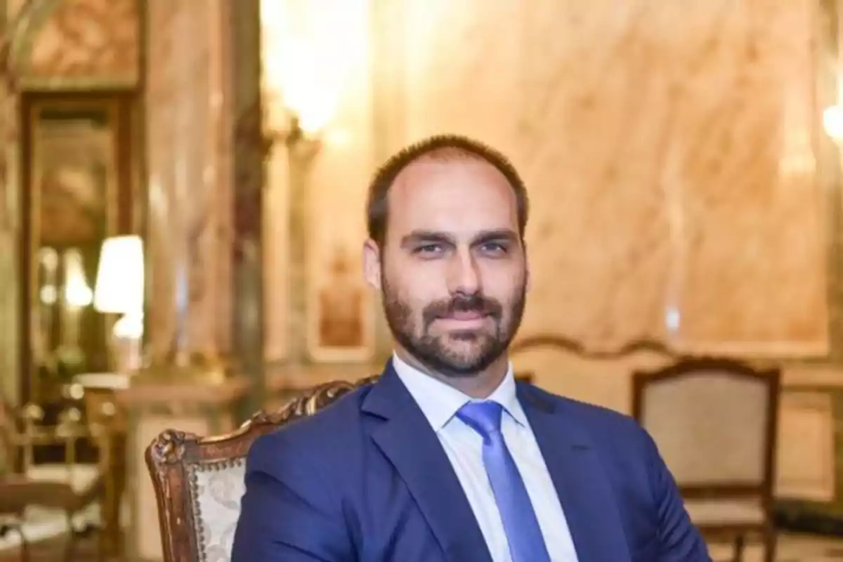 Man with a beard and a blue suit sitting on an elegant chair in a luxurious room with marble walls and classic furniture Man with a beard and a blue suit sitting on an elegant chair in a luxurious room with marble walls and classic furniture