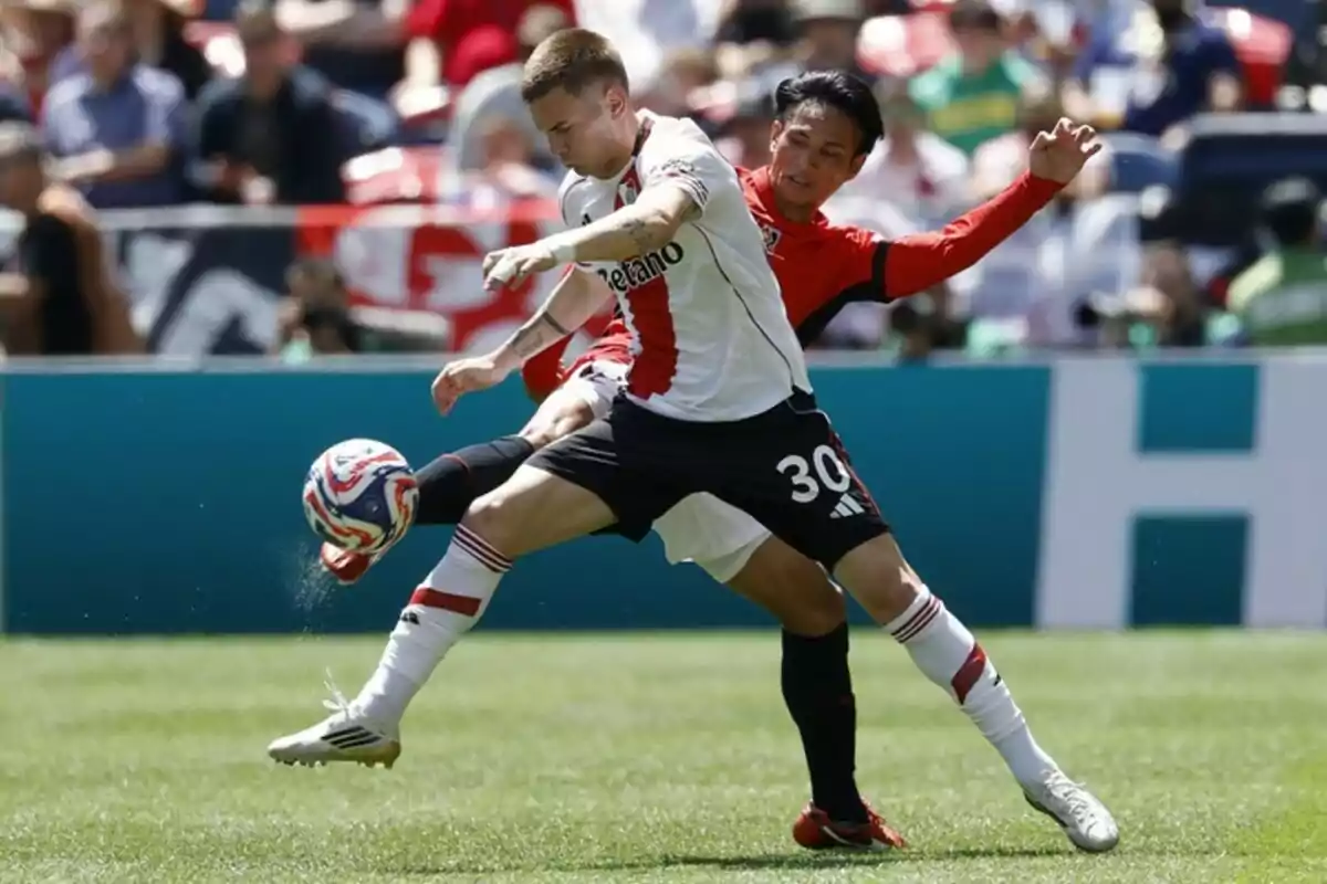 Two players compete for the ball during a match in a stadium full of spectators. Two players compete for the ball during a match in a stadium full of spectators.