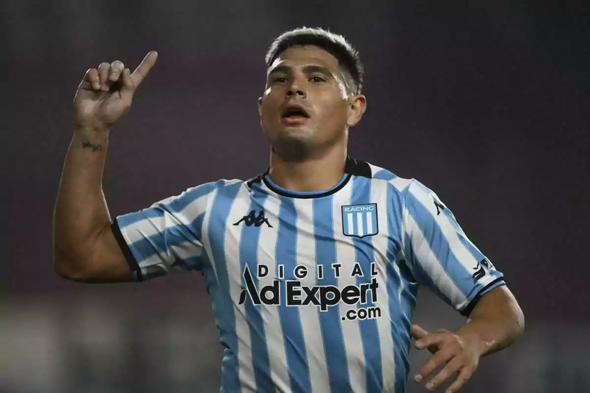 Soccer player wearing a Racing Club jersey celebrating on the field with his right arm raised Soccer player wearing a Racing Club jersey celebrating on the field with his right arm raised