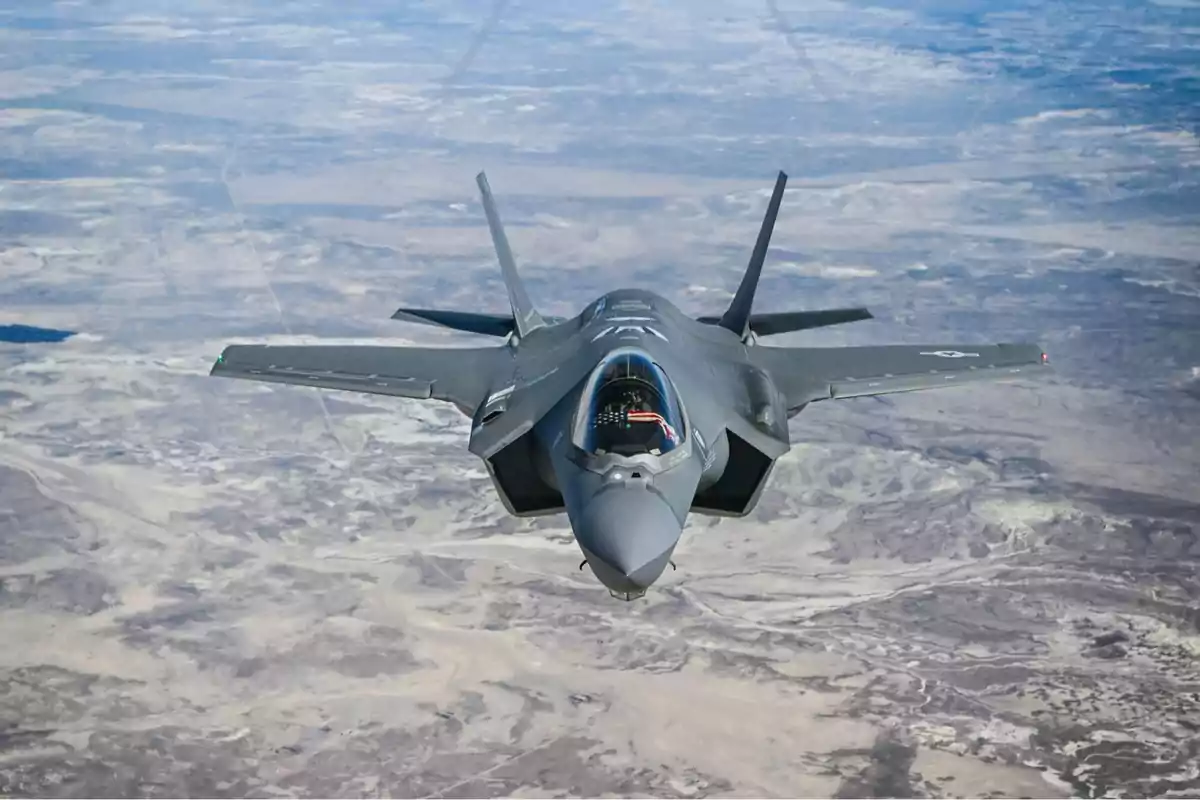 Avión de combate volando sobre un paisaje árido visto desde el aire