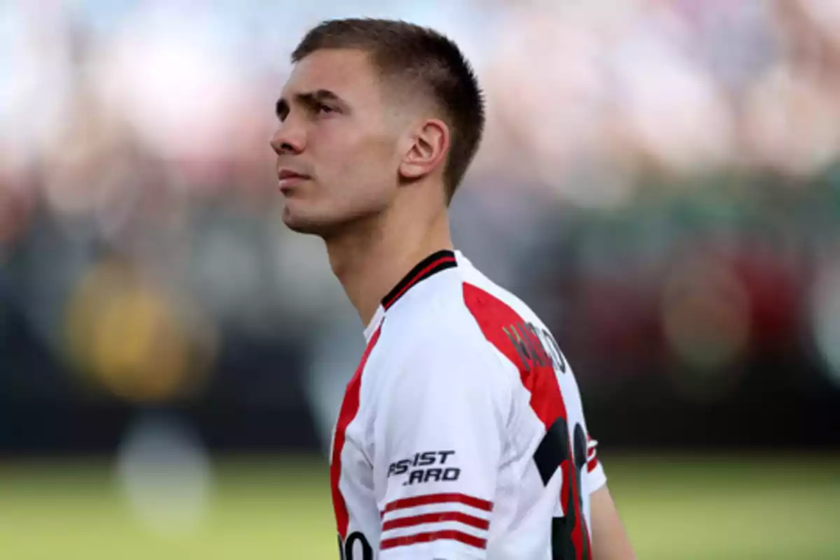 Soccer player wearing a white and red jersey looking up in a blurred stadium
