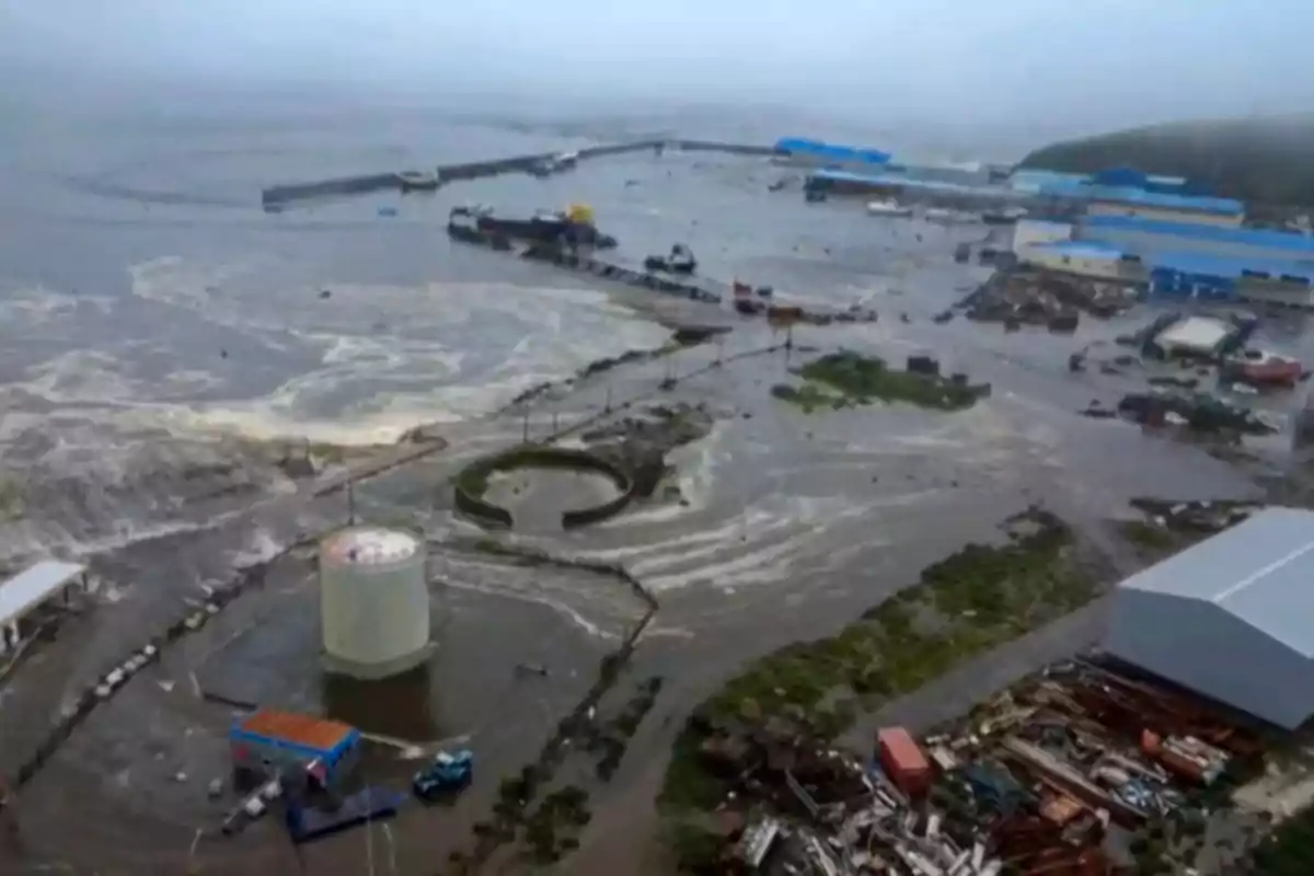 Aerial view of an industrial port flooded by a severe storm, with water covering much of the land and damaged structures Aerial view of an industrial port flooded by a severe storm, with water covering much of the land and damaged structures