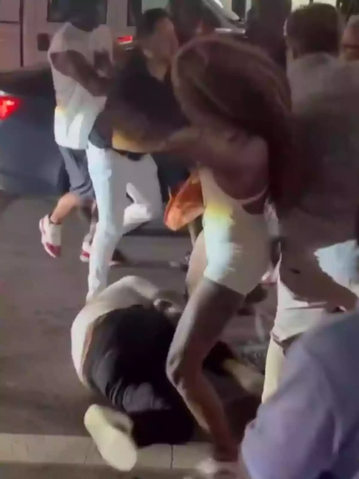 Varias personas involucradas en una pelea en la calle durante la noche, una persona está en el suelo mientras otras discuten y se empujan. Varias personas involucradas en una pelea en la calle durante la noche, una persona está en el suelo mientras otras discuten y se empujan.